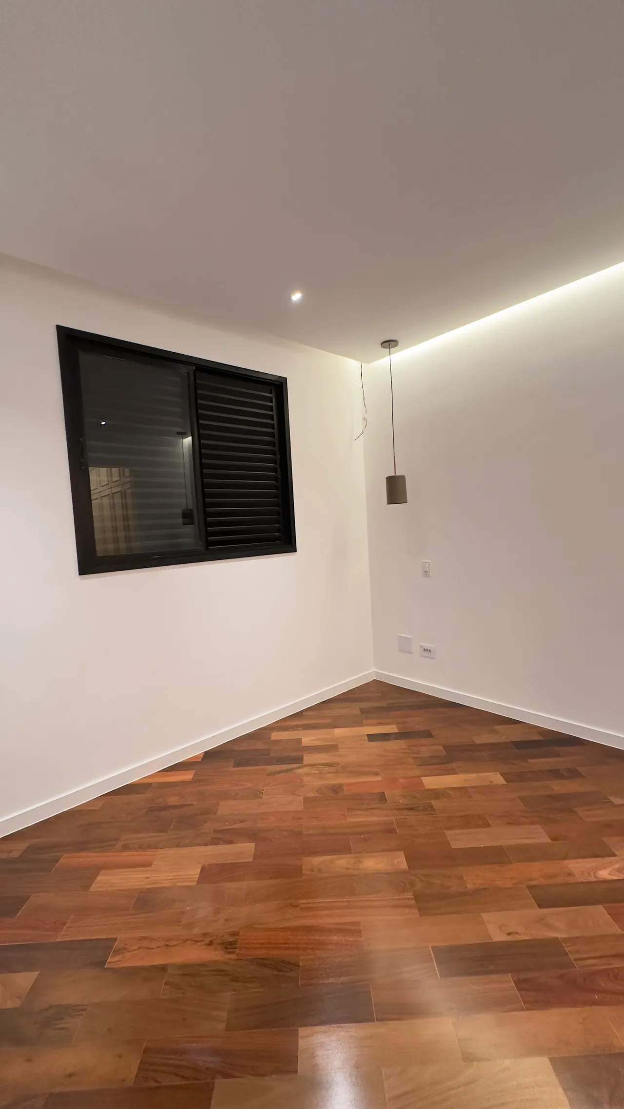 Quarto com piso madeira e iluminação linear