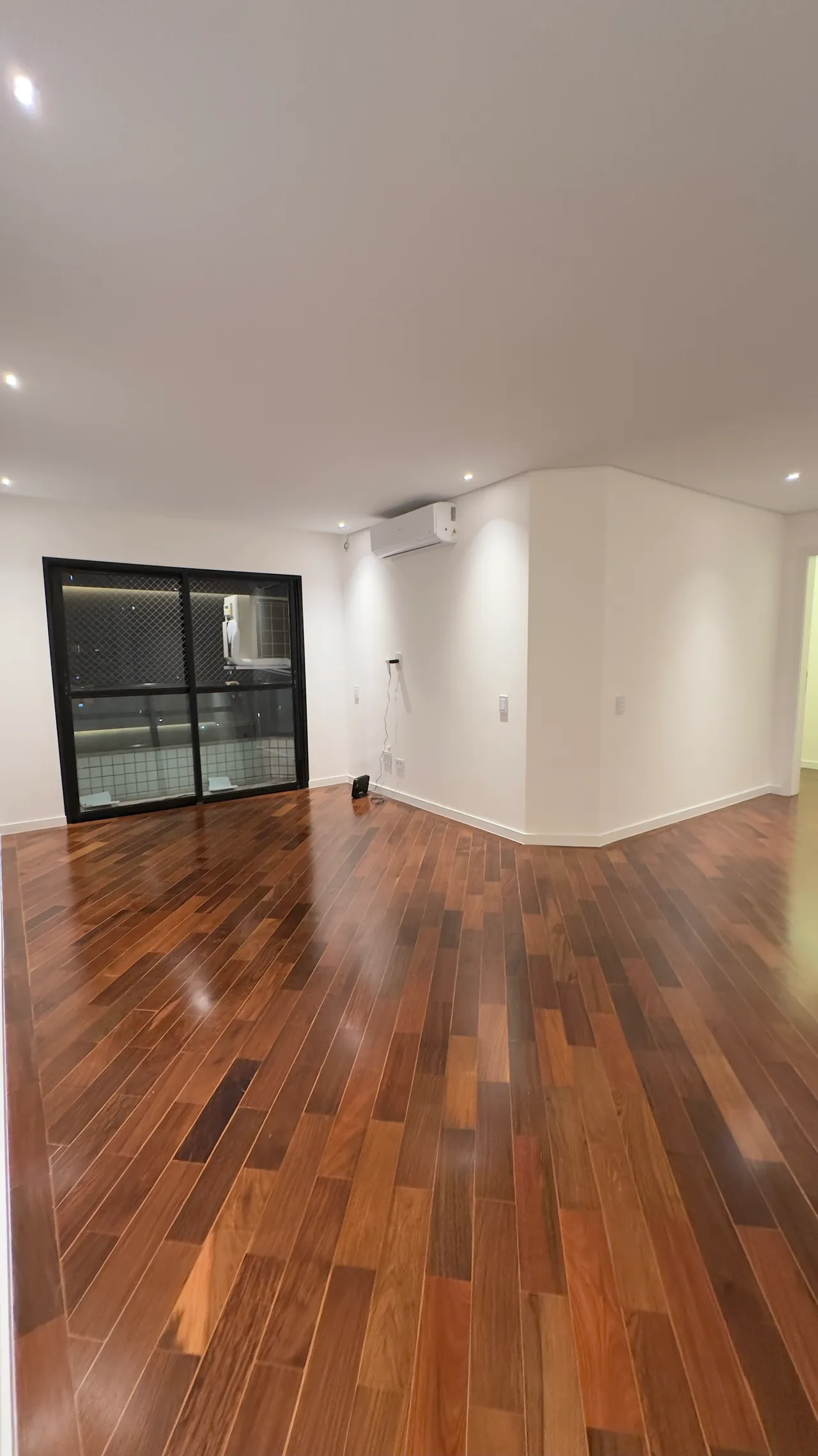 Sala integrada com varanda e piso madeira