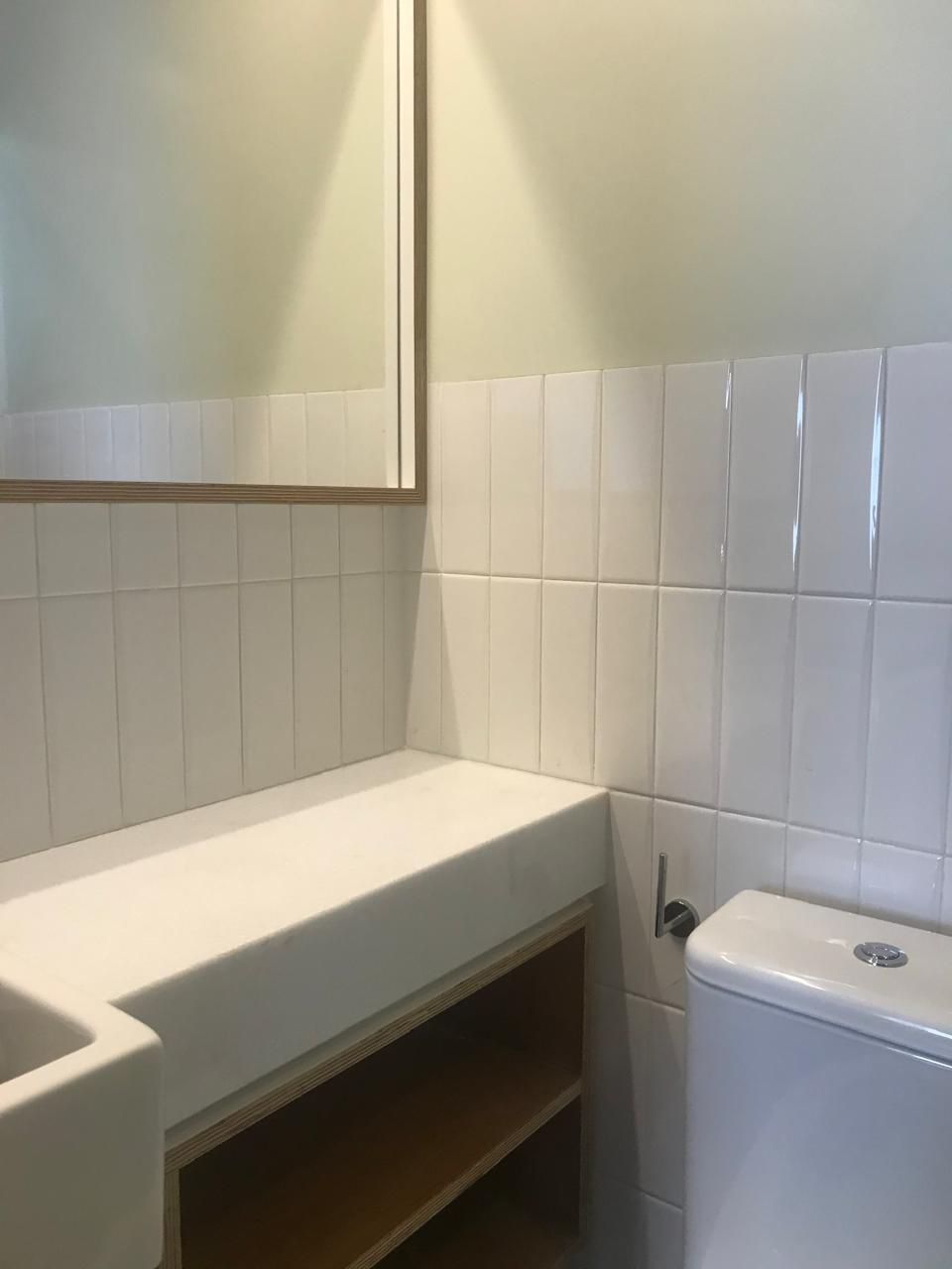 Banheiro com revestimento de azulejos e bancada em madeirado